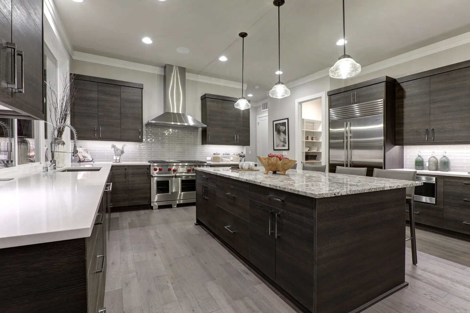 Modern gray kitchen features dark gray flat front cabinets paired with white quartz countertops and a glossy gray linear tile backsplash. Northwest, USA